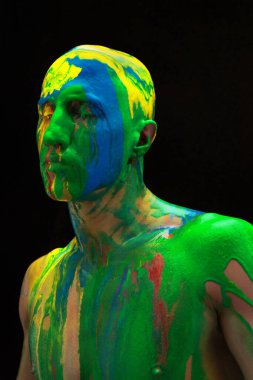 Çağdaş sanat eserleri. Siyah arka planda izole edilmiş renkli boyalarla kaplı renkli gözleri olan genç bir adam. İnsan vücudunda soyut sanat