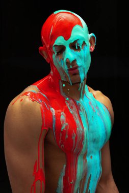 Genç adamın portresi mavi ve sarı boyayla kaplıydı. Kafasından omuzlarına ve vücuduna siyah arka planda izole bir şekilde akıyordu.