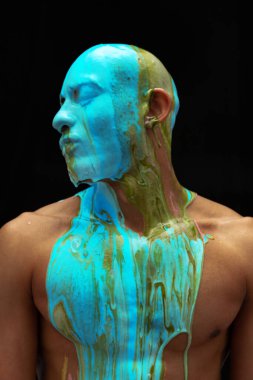 Siyah arka planda izole edilmiş koyu renkli boyayla kaplı genç kaslı adamın portresi.