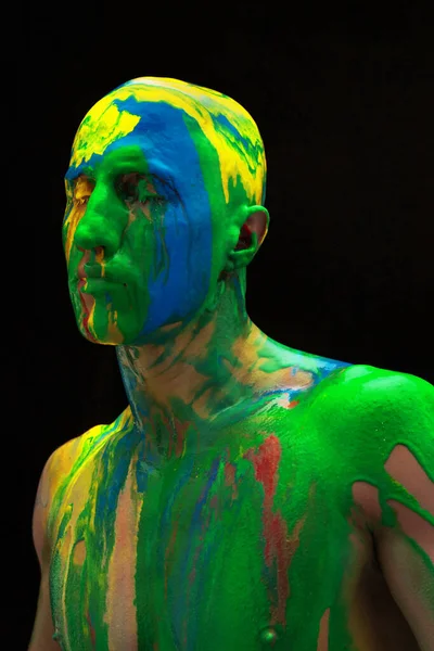 Çağdaş sanat eserleri. Siyah arka planda izole edilmiş renkli boyalarla kaplı renkli gözleri olan genç bir adam. İnsan vücudunda soyut sanat