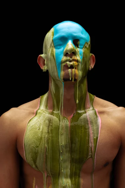 Portrait of young muscular man covered with thick paint isolated over black background — Photo