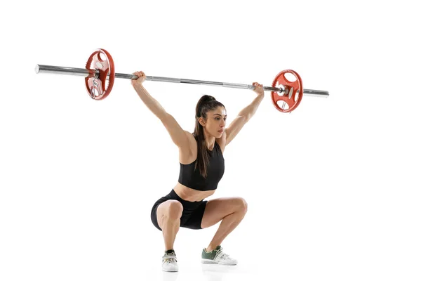 Retrato de comprimento total de mulher musculada em sportswear exercício com um peso, barra isolada em fundo branco. Esporte, conceito de levantamento de peso — Fotografia de Stock