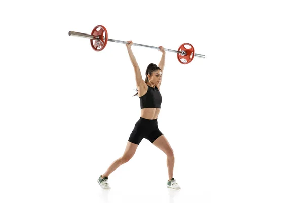 スポーツウェアの運動中の筋肉質の女性の完全な長さの肖像画は、白い背景に隔離された鐘。スポーツ、重量挙げの概念 — ストック写真