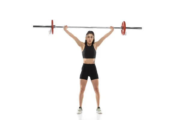 Полноразмерный портрет мускулистой женщины в спортивной одежде, упражняющейся с весом, штанга изолирована на белом фоне. Спорт, концепция тяжелой атлетики — стоковое фото