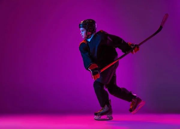 Portrait of boy, child, hockey player training, practising isolat over purple background in neon light — Stok Foto