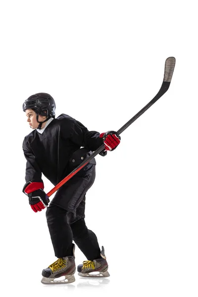 Side view. Portrait of concentrated boy, child, hockey player in motion, training isolated over white background. — ストック写真