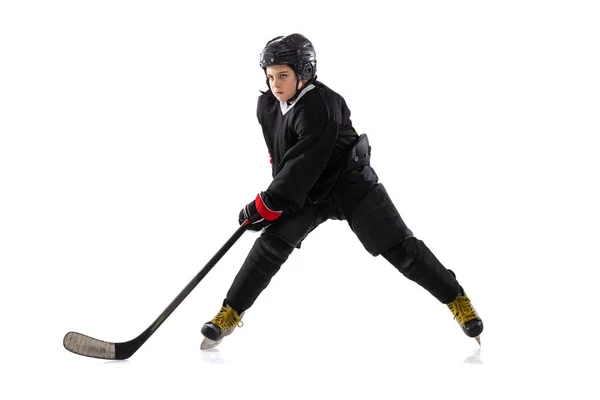 Dynamic portrait of kid, hockey player in black sportswear and helmet training isolated over white studio background — ストック写真