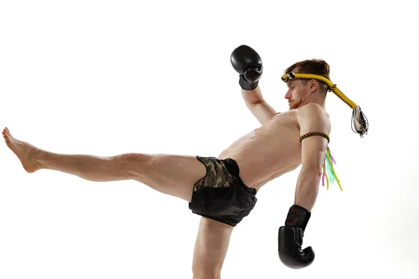 Студійний знімок молодого професійного тайського боксера, який практикується ізольовано на білому фоні студії. Спорт, мюай тай, змагання, концепція бойового клубу — стокове фото