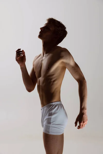 Moderno, desprezo. Homem artístico jovem, dançarino masculino flexível dançando isolado em fundo de estúdio cinza. Arte, movimento, flexibilidade, conceito de inspiração. — Fotografia de Stock