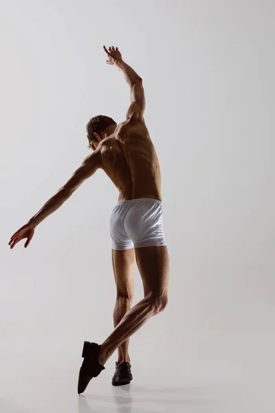 Baile temporal, actuación. Joven hombre sin camisa flexible en ropa interior bailando aislado sobre fondo gris. Arte, música, belleza. concepto de estilo de vida saludable — Foto de Stock