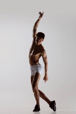 Düşünce dansı, performans. Gri arka planda yalnız dans eden, iç çamaşırlı, esnek, genç bir adam. Sanat, müzik, güzellik. Sağlıklı yaşam tarzı kavramı
