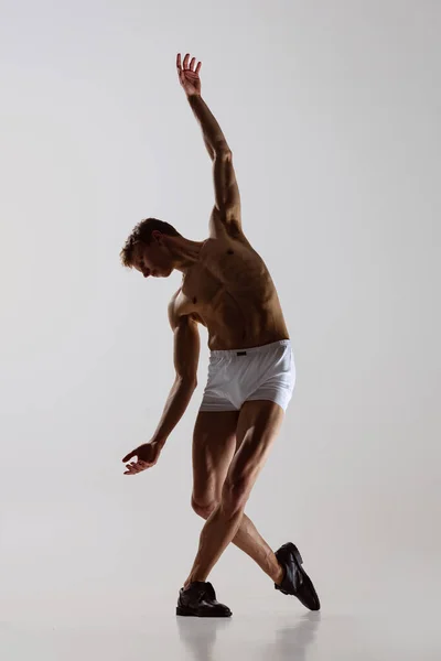 Taniec kontemplacyjny, występ. Młody, elastyczny mężczyzna w bieliźnie tańczący na szarym tle. Sztuka, muzyka, piękno. Koncepcja zdrowego stylu życia — Zdjęcie stockowe