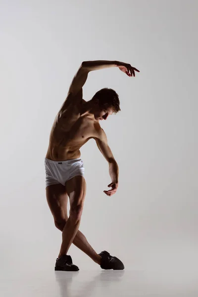 Tempotanz, Performance. Junger flexibler Mann in Unterwäsche, der isoliert auf grauem Hintergrund tanzt. Kunst, Musik, Schönheit. Gesunder Lebensstil — Stockfoto