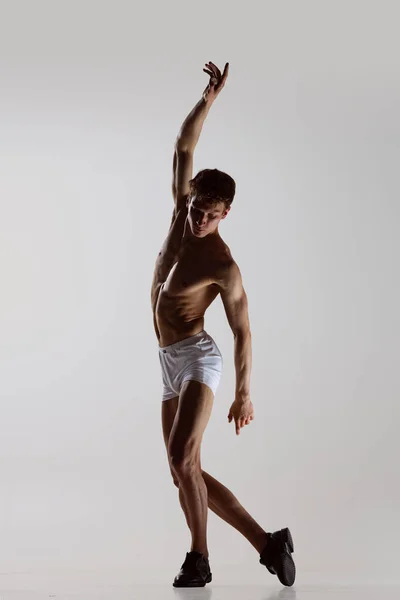 Contemp dance, performance. Jovem homem sem camisa flexível em roupa interior dançando isolado em fundo cinza. Arte, música, beleza. Conceito de estilo de vida saudável — Fotografia de Stock