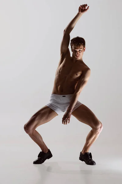 Contemp dans, optreden. Jonge flexibele shirtloze man in ondergoed dansen geïsoleerd op grijze achtergrond. Kunst, muziek, schoonheid. Gezond levensstijl concept — Stockfoto