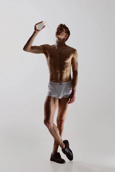 Dlouhý portrét mladého pohledného sportovního muže bez košile v bílých boxerských kalhotkách se hladce pohybuje na bílém pozadí. Wellness, fitness, beauty concept. — Stock fotografie