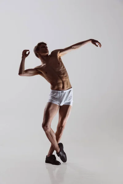 Moderno, contemp. Joven hombre artístico, bailarín masculino flexible bailando aislado sobre fondo gris estudio. Arte, movimiento, flexibilidad, concepto de inspiración. — Foto de Stock