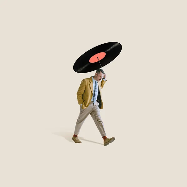 Contemporary art collage. Stylish thoughtul man walking under retro vinyl record isolated over light gray background — ストック写真