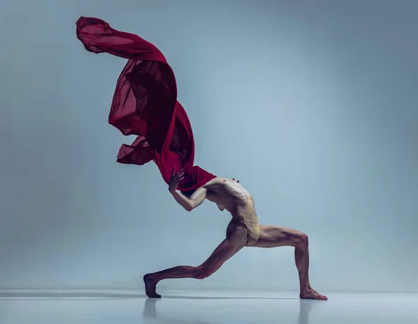 Ritratto di giovane, ballerino flessibile in azione con tessuto rosso, tessuto isolato su fondo navy studio. Grace, arte, concetto di bellezza. — Foto Stock