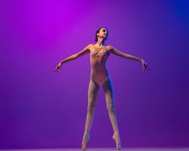 Esnek bir bayan balerin, sahne kıyafetli bir genç kız ve mor arka planda izole bir şekilde dans ediyor. Sanat, zarafet, güzellik, bale okulu konsepti