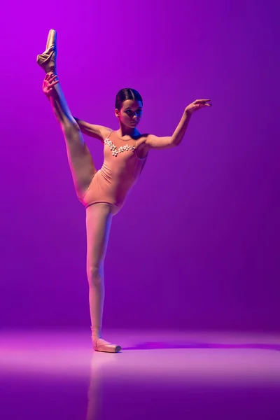 若い小さなバレエダンサーの肖像画、 10代の練習、ネオンで紫色の背景に孤立したダンス。アート、優雅さ、美しさ、バレエ学校のコンセプト — ストック写真