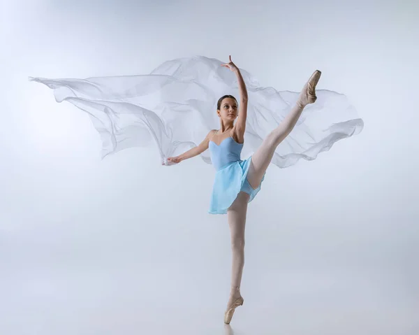 Una joven, aspirante a bailarina en vestido azul y puntas bailando con tela aislada sobre fondo gris. Arte, gracia, belleza, concepto de escuela de ballet —  Fotos de Stock