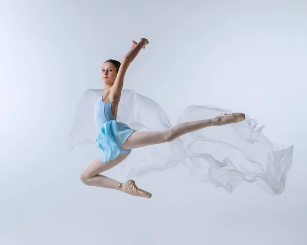 One young girl, aspiring ballerina in blue dress and pointes dancing with cloth isolated on gray background. Art, grace, beauty, ballet school concept — Photo