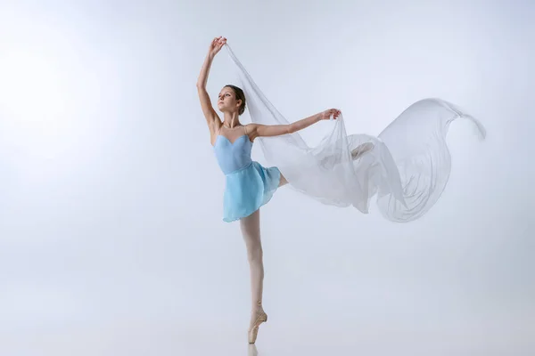 Menina bonita, aspirante a bailarina em vestido azul e pointes dançando com pano isolado em fundo cinza. Arte, graça, beleza, conceito de escola de balé — Fotografia de Stock