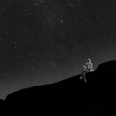 Çağdaş sanat kolajı. Geceleyin kayanın üzerinde oturan zarif genç kadın yıldızlı arka planda izole edilmiş.