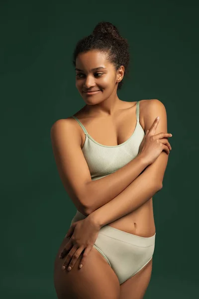 Portrait of young beautiful woman posing in comfortable cotton underwear isolated over green studio background. Self-love concept — стоковое фото