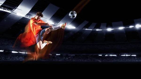 懐中電灯付きスタジアムでのアクションでプロサッカーやサッカー選手,ゴールを獲得するためのボールを蹴ります.スポーツ、競争、運動、克服の概念. — ストック写真