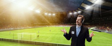 Oyun tahminleri. Ciddi adam, profesyonel spor yorumcusu spor stadyumunun arka planında izole edilmiş online futbol maçı yayınına sahip.