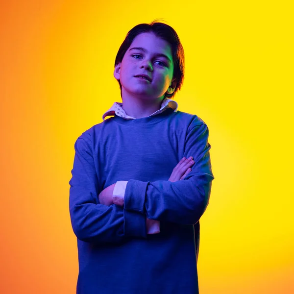 Portrait of little boy, child in blue sweater posing isolated over yellow background in neon light — Foto de Stock