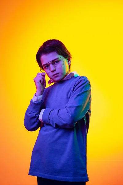 Portrait of little boy, child in blue sweater and trendy glasses posing isolated over yellow background in neon light —  Fotos de Stock