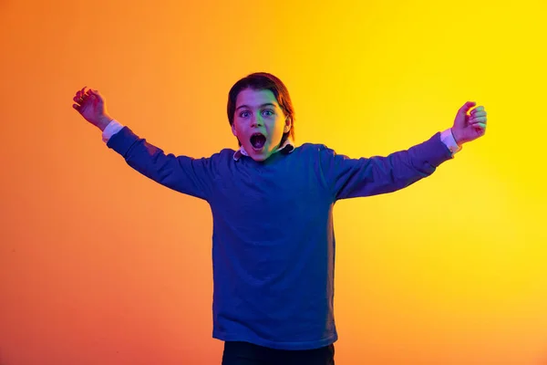 Πορτρέτο του χαριτωμένο αγόρι, το παιδί δείχνει συναίσθημα του ενθουσιασμού, εξαπλώνοντας τα χέρια και ουρλιάζοντας απομονώνονται σε κίτρινο φόντο σε νέον — Φωτογραφία Αρχείου