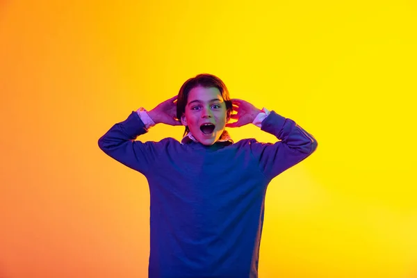 Portret chłopca, radosne krzyki dziecka, pozowanie na żółtym tle pracowni w neonowym świetle — Zdjęcie stockowe