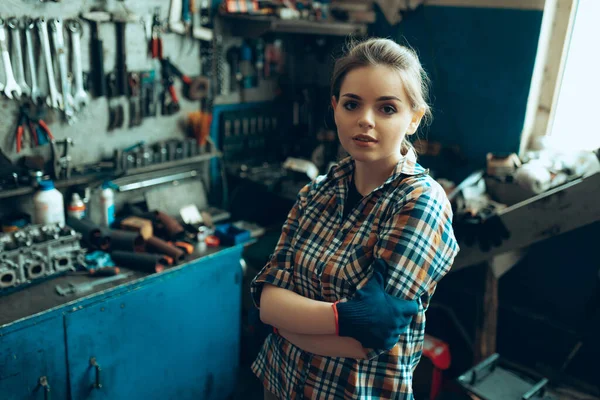 Портрет молодой уверенной девушки в рабочей одежде, стоящей на автозаправке, в помещении. Гендерное равенство. Но, к сожалению, это не так уж и важно. — стоковое фото