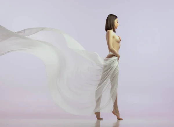 Pełnowymiarowy portret młodej czułej kobiety pozującej nago, ciało pokryte jedwabną tkaniną odizolowane na jasnoróżowym tle. Widok boczny — Zdjęcie stockowe