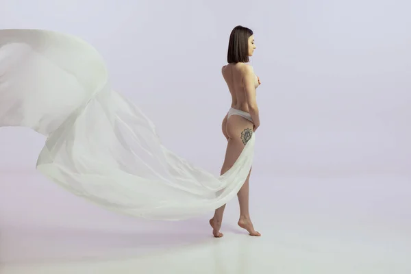 Portret młodej czułej kobiety pozującej nago, ciało pokryte jedwabną tkaniną odizolowane na jasnoróżowym tle — Zdjęcie stockowe