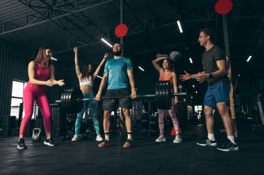 Spor yapan bir grup genç arkadaş, spor salonunda antrenman yapıyorlar.