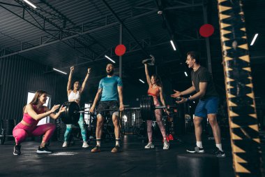 Spor yapan bir grup genç, spor salonunda antrenman yapıyor. Arkadaşlar ağırlık kaldırma başarısı olan adamı alkışlıyor.