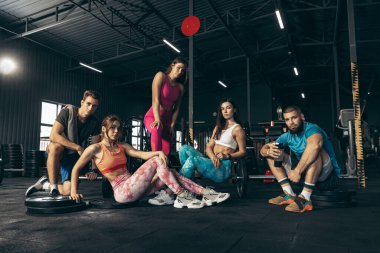 Spor yapan bir grup genç arkadaş, spor salonunda antrenman yapıyorlar. Serinlemek, dinlenmek, poz vermek.