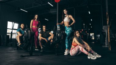 Spor yapan bir grup genç arkadaş, spor salonunda antrenman yapıyorlar. Sportif yaşam tarzını sürdürmek