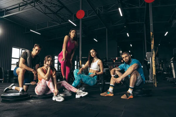 Grupa młodych przyjaciół uprawiających sport, trenujących na siłowni w pomieszczeniach. Pojęcie zdrowia, sportowy styl życia, sprawność — Zdjęcie stockowe