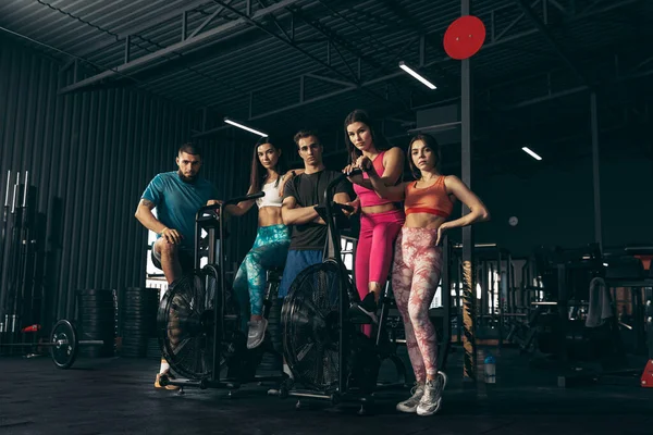 Spor yapan bir grup genç arkadaş, spor salonunda antrenman yapıyorlar. Egzersiz bisikletinde kadın eğitimi. Pozisyon