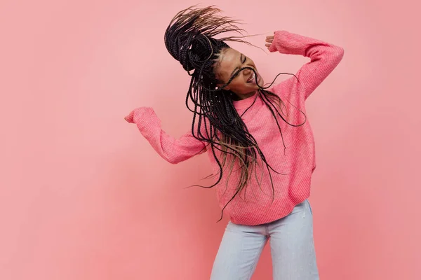 Студійний знімок молодої збудженої дівчини з афро зачіскою в повсякденному стилі, розважається ізольовано на рожевому фоні. Поняття краси, мистецтва, моди, молоді, стилю — стокове фото