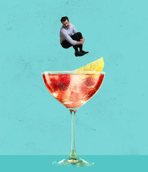 Contemporary art collage. Happy cheerful man jumping into refreshing tasty cocktail with fruity taste isolated over blue background — ストック写真