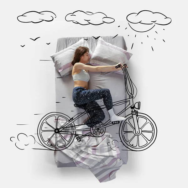 Creative image. Top view of young woman lying on bed, sleeping, dreaming about riding bike — Photo