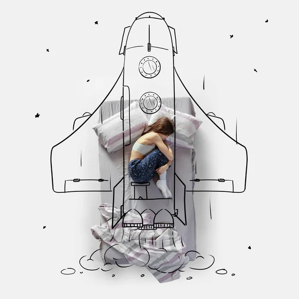 Creative image. Top view of young woman lying on bed, sleeping, dreaming about flying on a rocket — Stock Photo, Image
