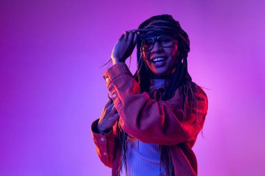 Portrait of female fashion model in cotton shirt isolated on purple background in neon light. Concept of beauty, art, fashion, youth and emotions